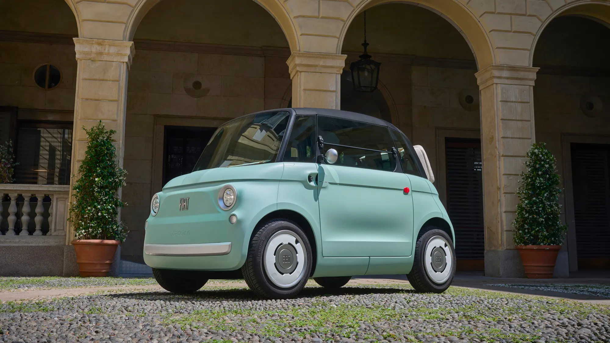 Πράσινο ηλεκτρικό FIAT Topolino μπροστά από ιστορικό κτίριο